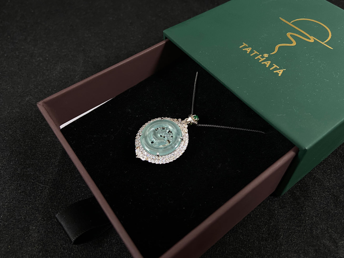 A circular pendant features a light green jade deer enclosed within a jade ring, all framed in 925 silver.
