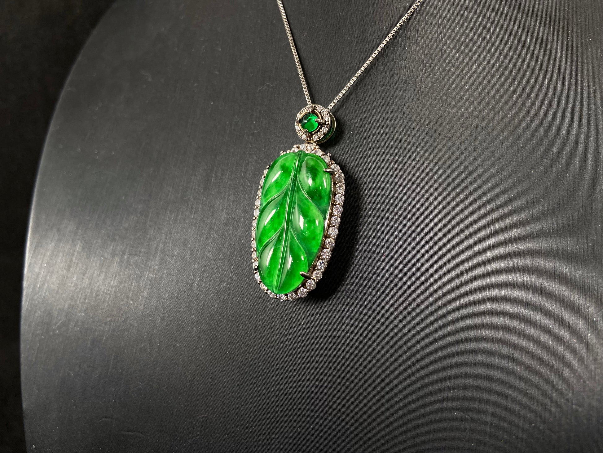 A leaf shaped emerald jadeite pendant, elegantly framed by a 925 sterling silver border.