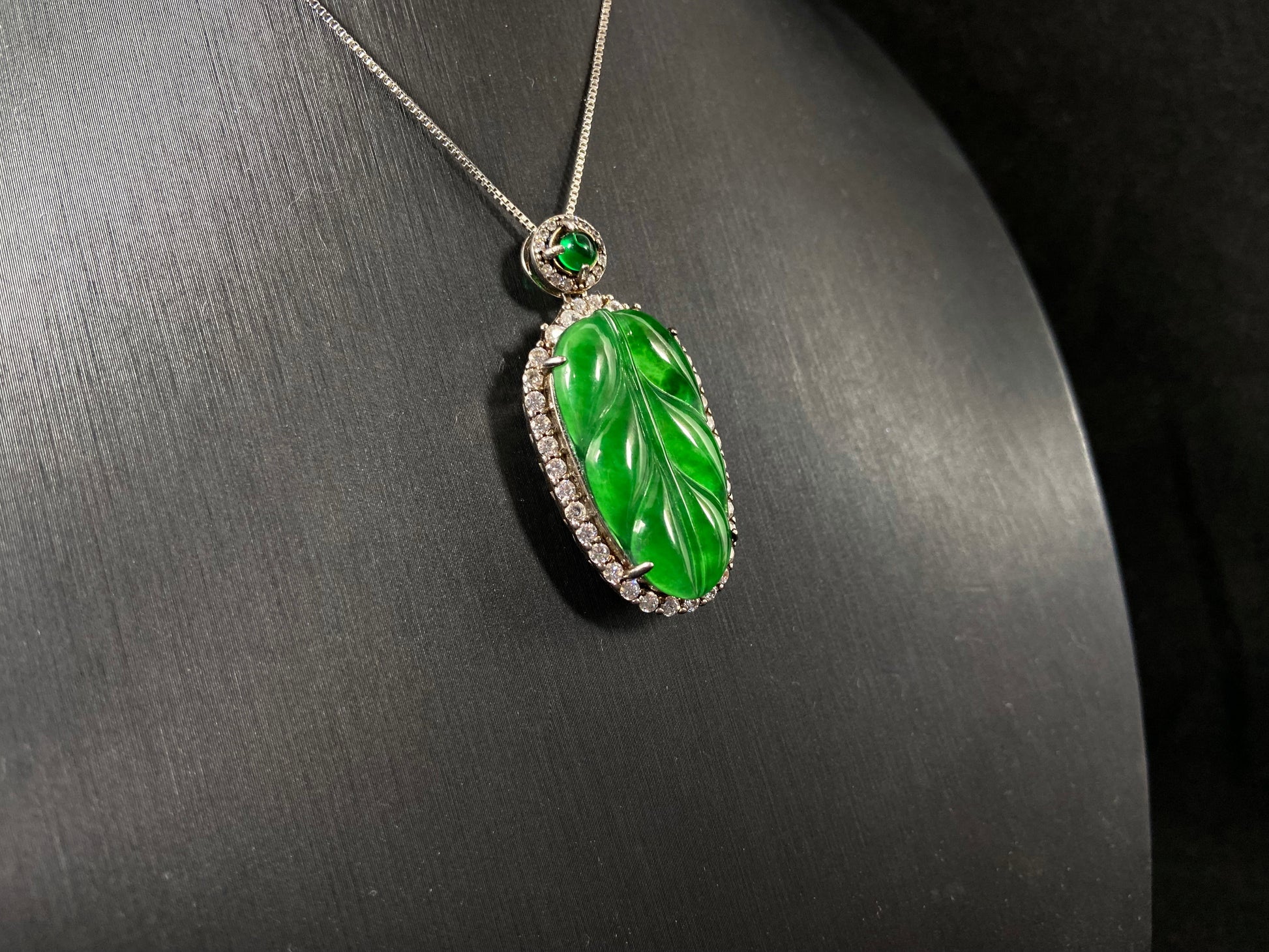 A leaf shaped emerald jadeite pendant, elegantly framed by a 925 sterling silver border.