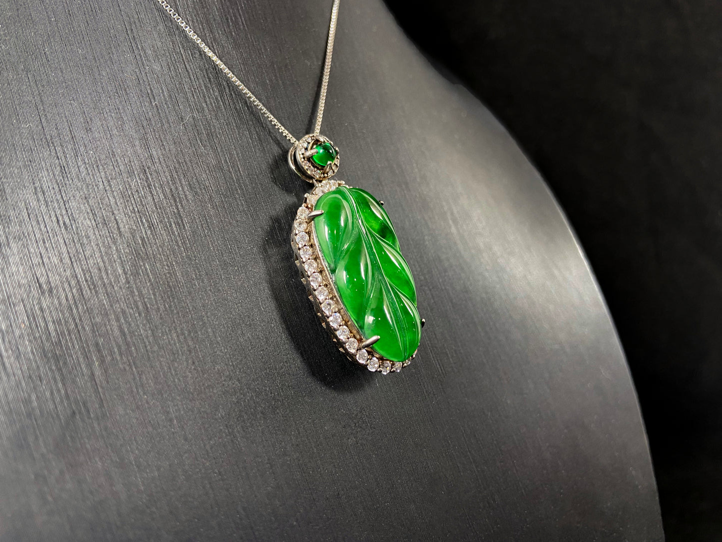 A leaf shaped emerald jadeite pendant, elegantly framed by a 925 sterling silver border.