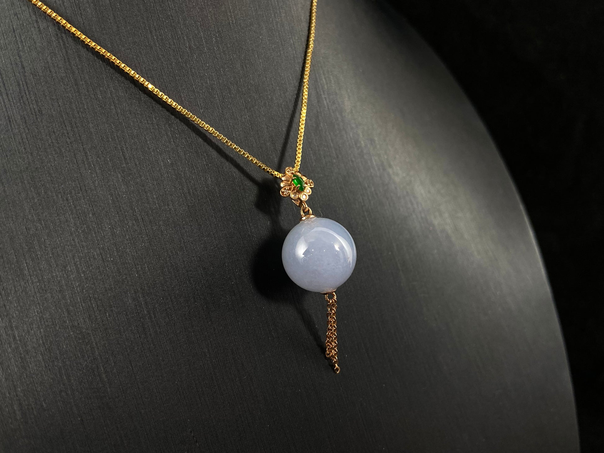 A semi-transparent, milky white jade bead is securely set using the nail-set technique