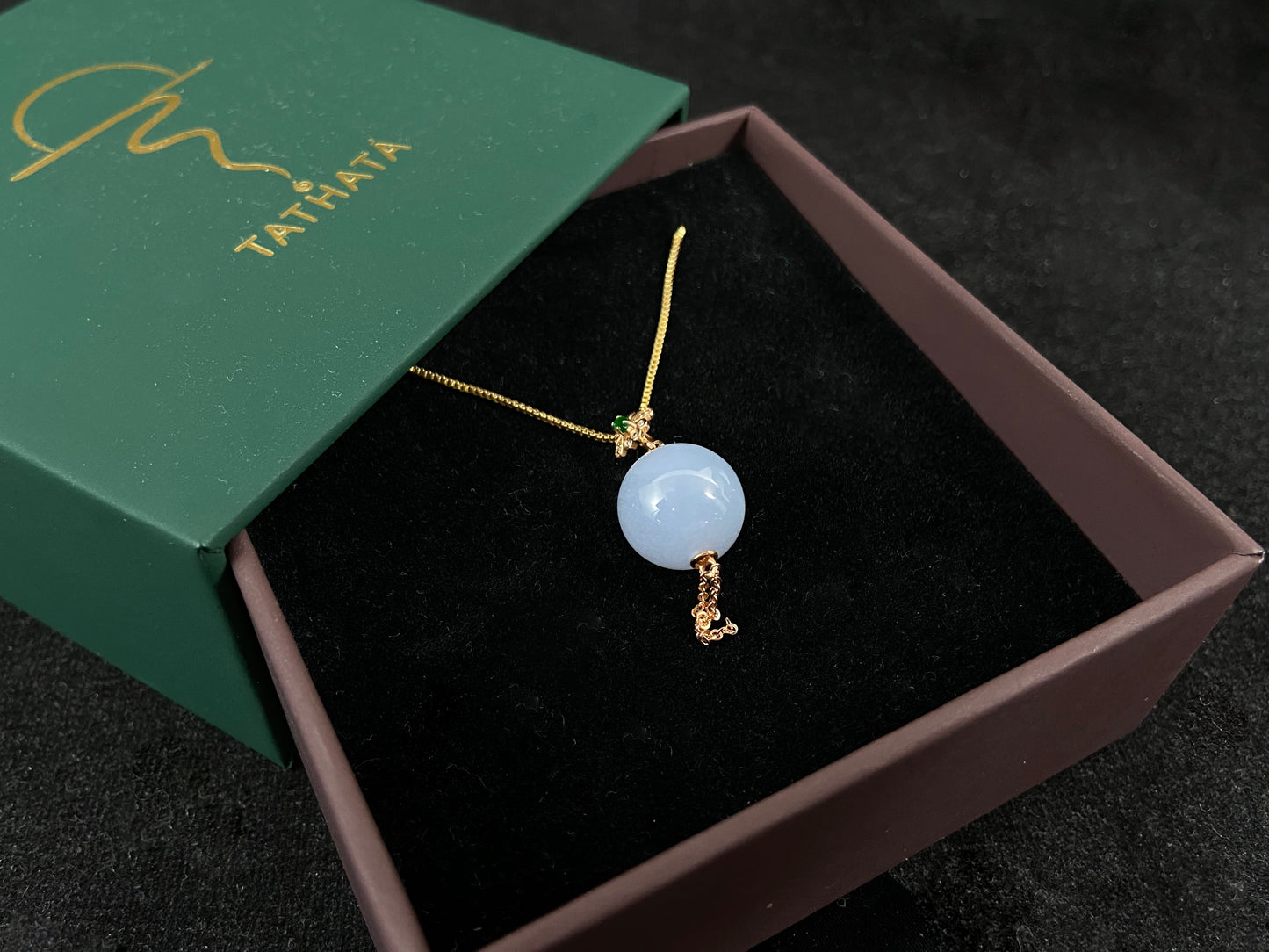 A semi-transparent, milky white jade bead is securely set using the nail-set technique