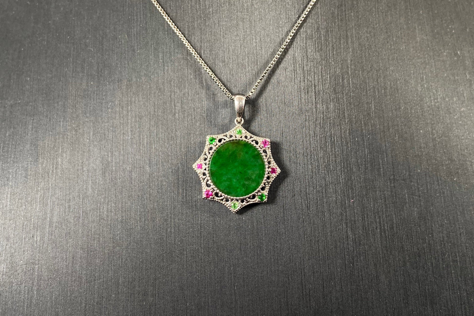 A circular imperial green jade center is elegantly encased within an octagonal frame of 18k white gold.