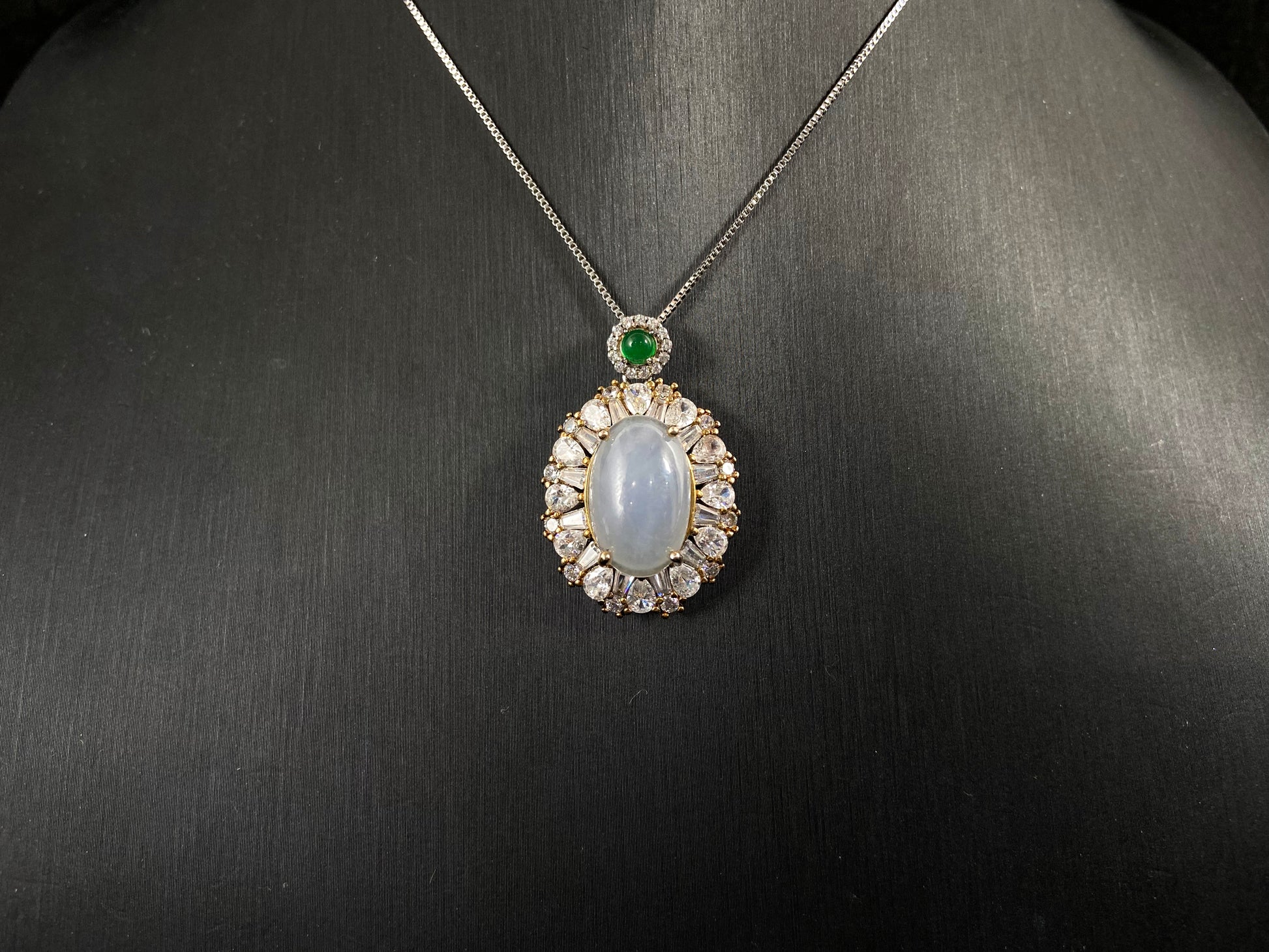 An oval, semi translucent milky jade pendant is securely embraced by a 925 silver claw set frame.