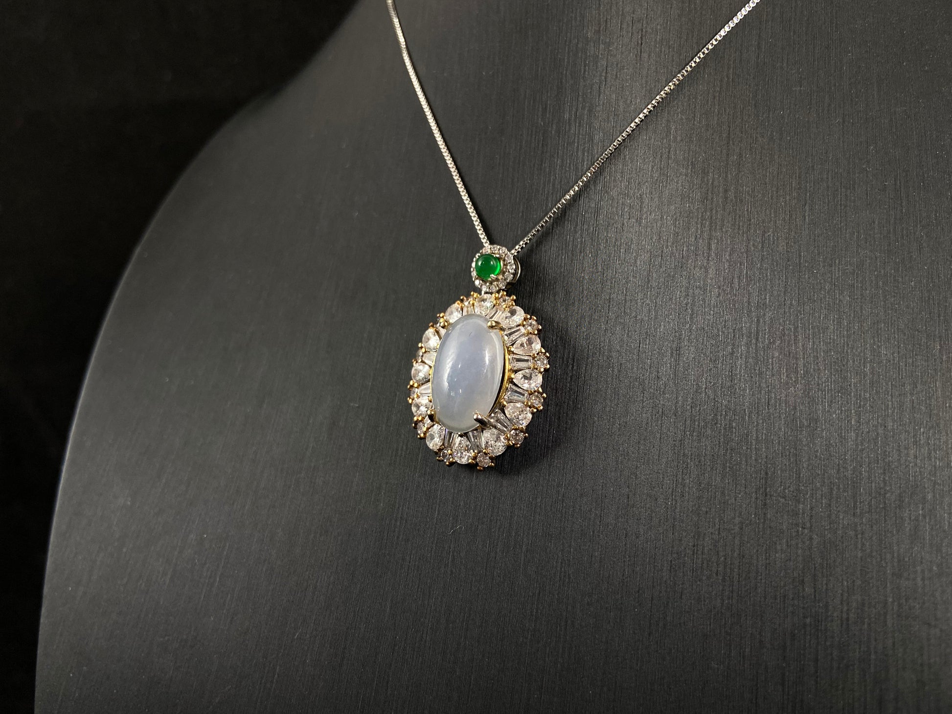 An oval, semi translucent milky jade pendant is securely embraced by a 925 silver claw set frame.