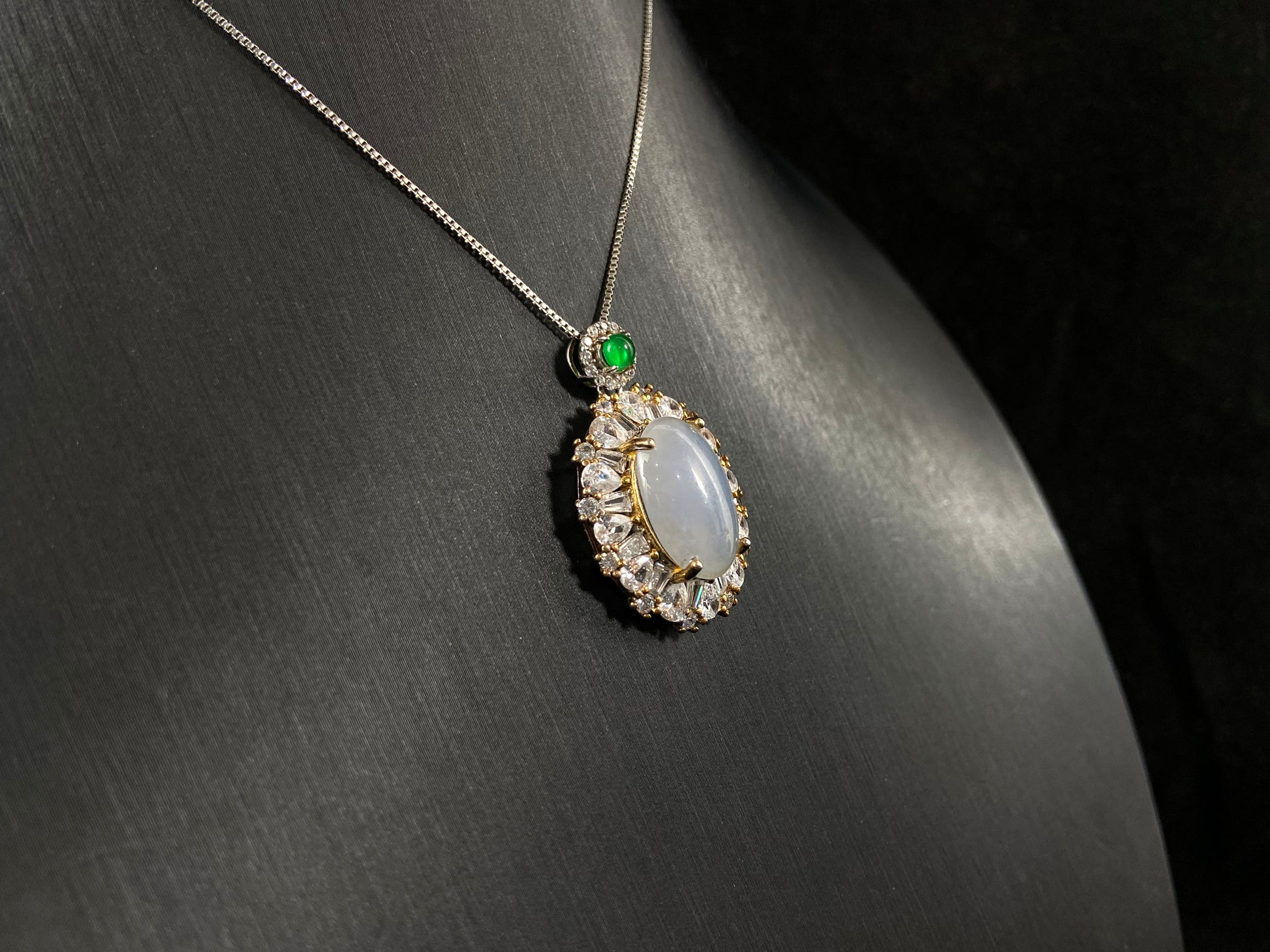 An oval, semi translucent milky jade pendant is securely embraced by a 925 silver claw set frame.