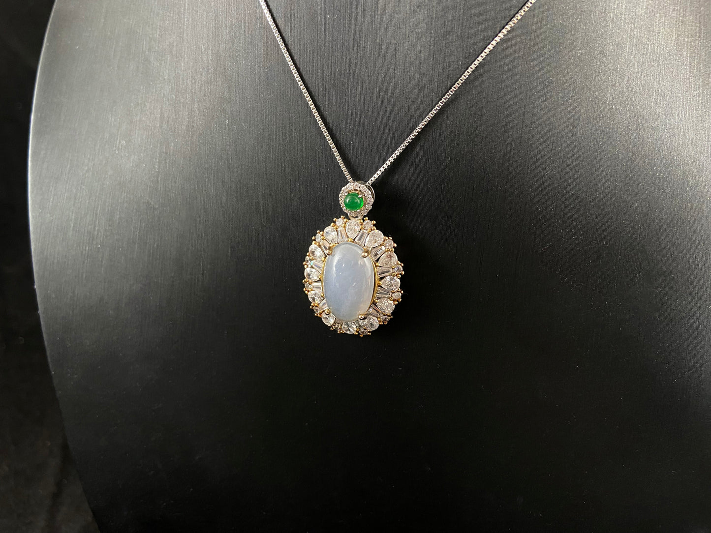 An oval, semi translucent milky jade pendant is securely embraced by a 925 silver claw set frame.