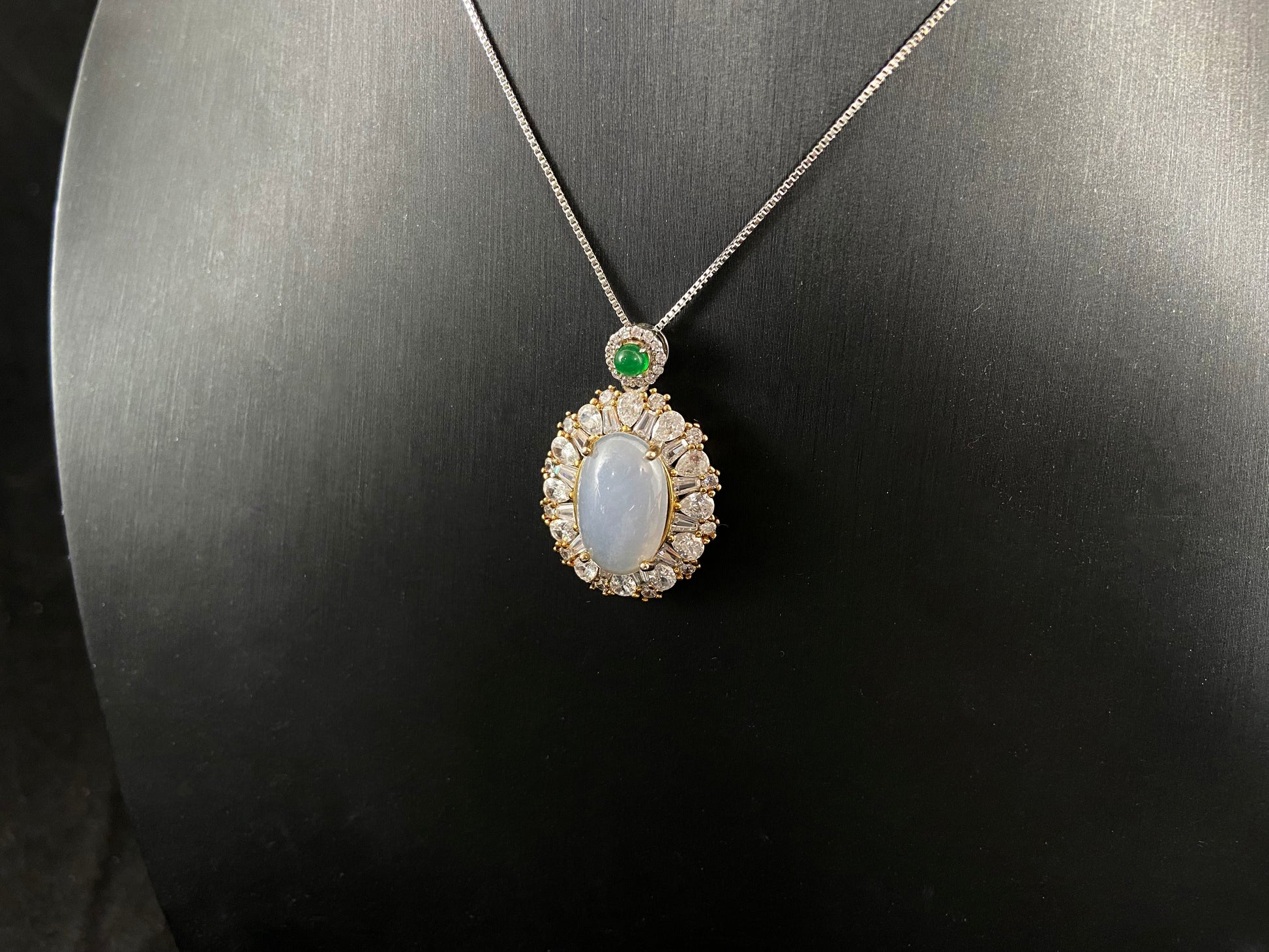 An oval, semi translucent milky jade pendant is securely embraced by a 925 silver claw set frame.