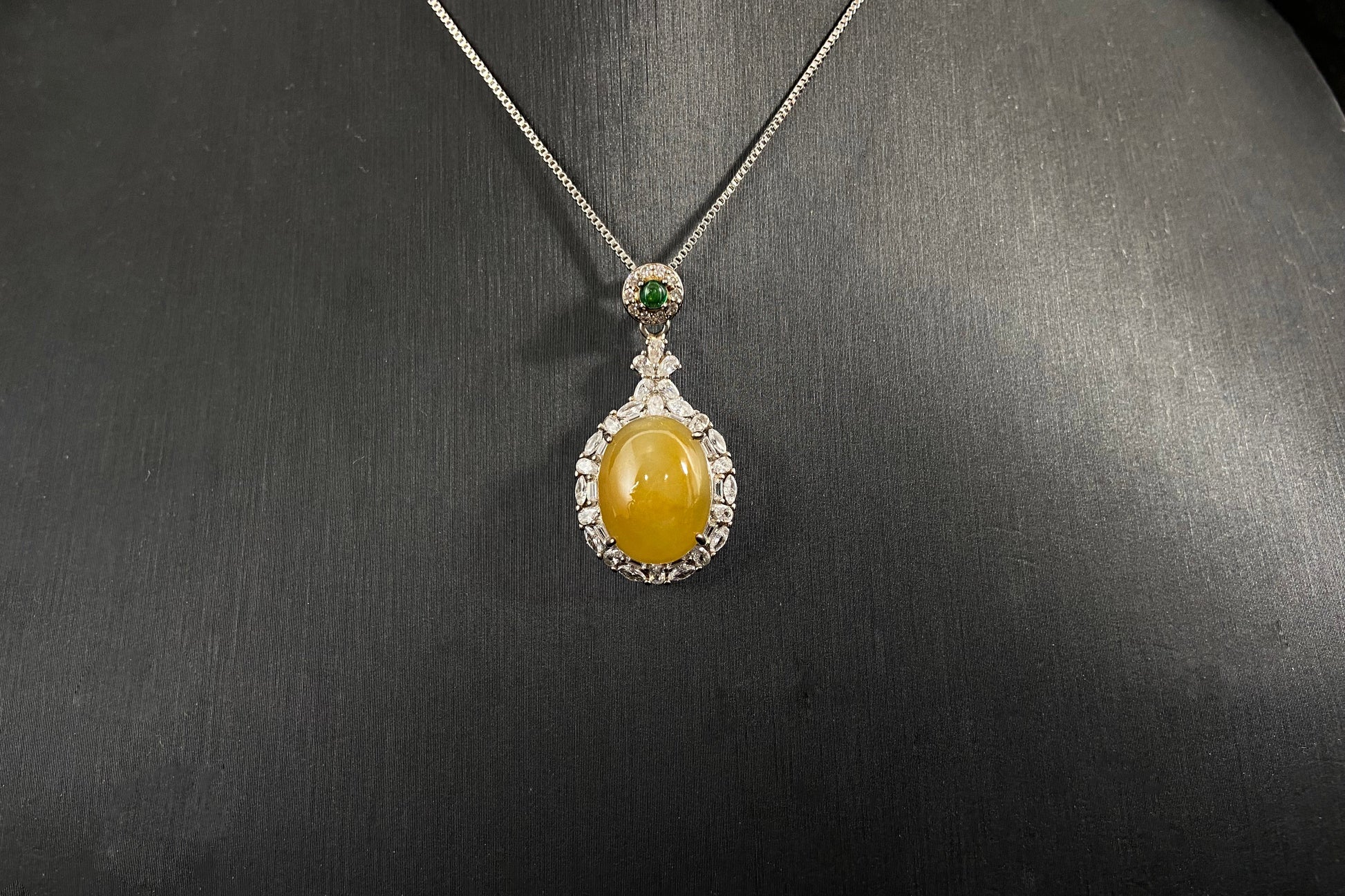 This yellow circular jade pendant features a claw set 925 silver frame that securely embraces the gemstone.