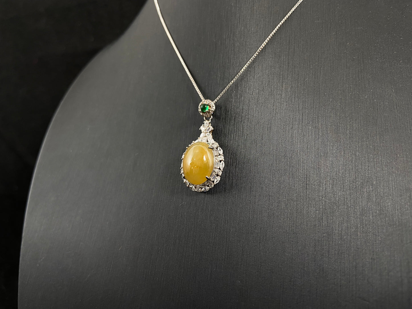 This yellow circular jade pendant features a claw set 925 silver frame that securely embraces the gemstone.