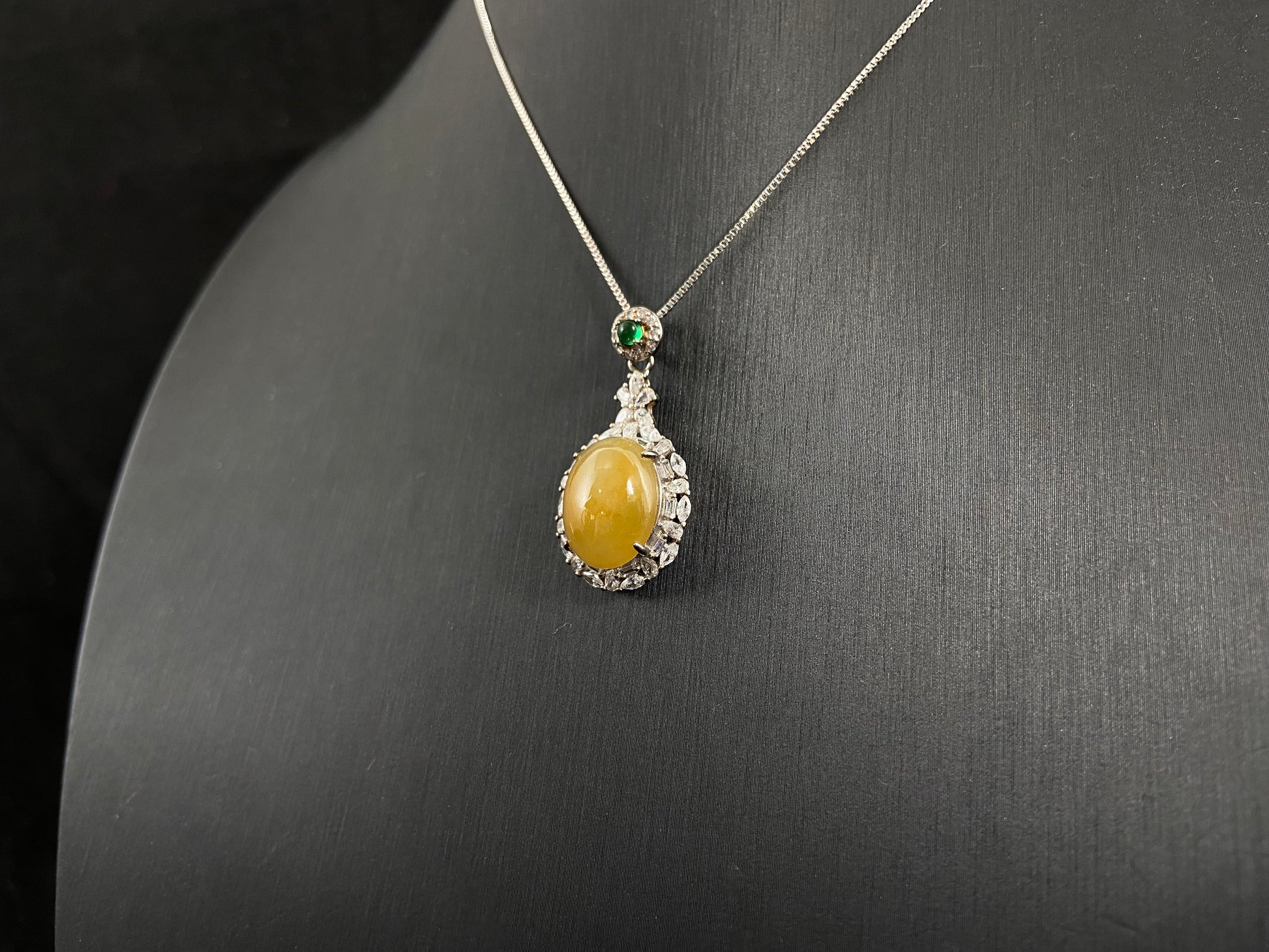 This yellow circular jade pendant features a claw set 925 silver frame that securely embraces the gemstone.