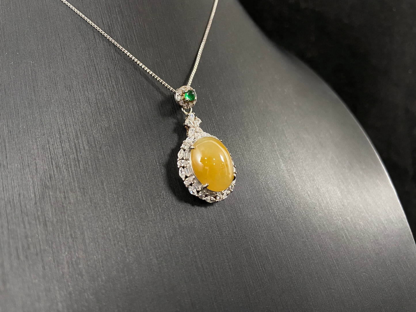 This yellow circular jade pendant features a claw set 925 silver frame that securely embraces the gemstone.