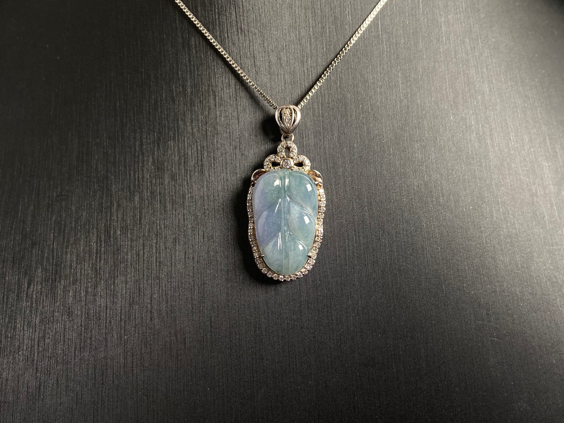 A leaf shaped jade pendant featuring translucent green blending into soft purple, elegantly framed in 925 silver.