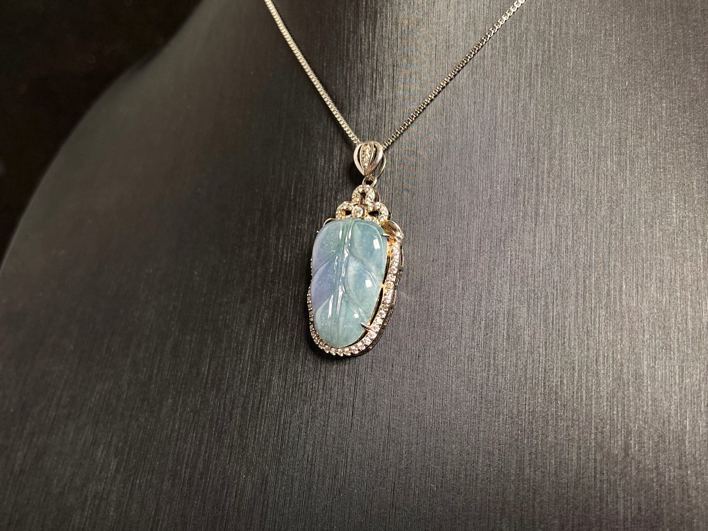 A leaf shaped jade pendant featuring translucent green blending into soft purple, elegantly framed in 925 silver.