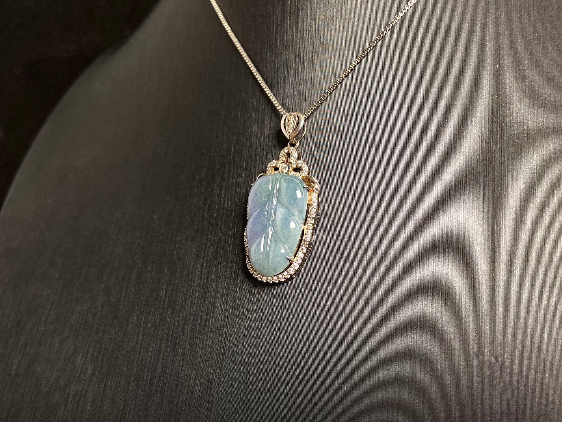 A leaf shaped jade pendant featuring translucent green blending into soft purple, elegantly framed in 925 silver.