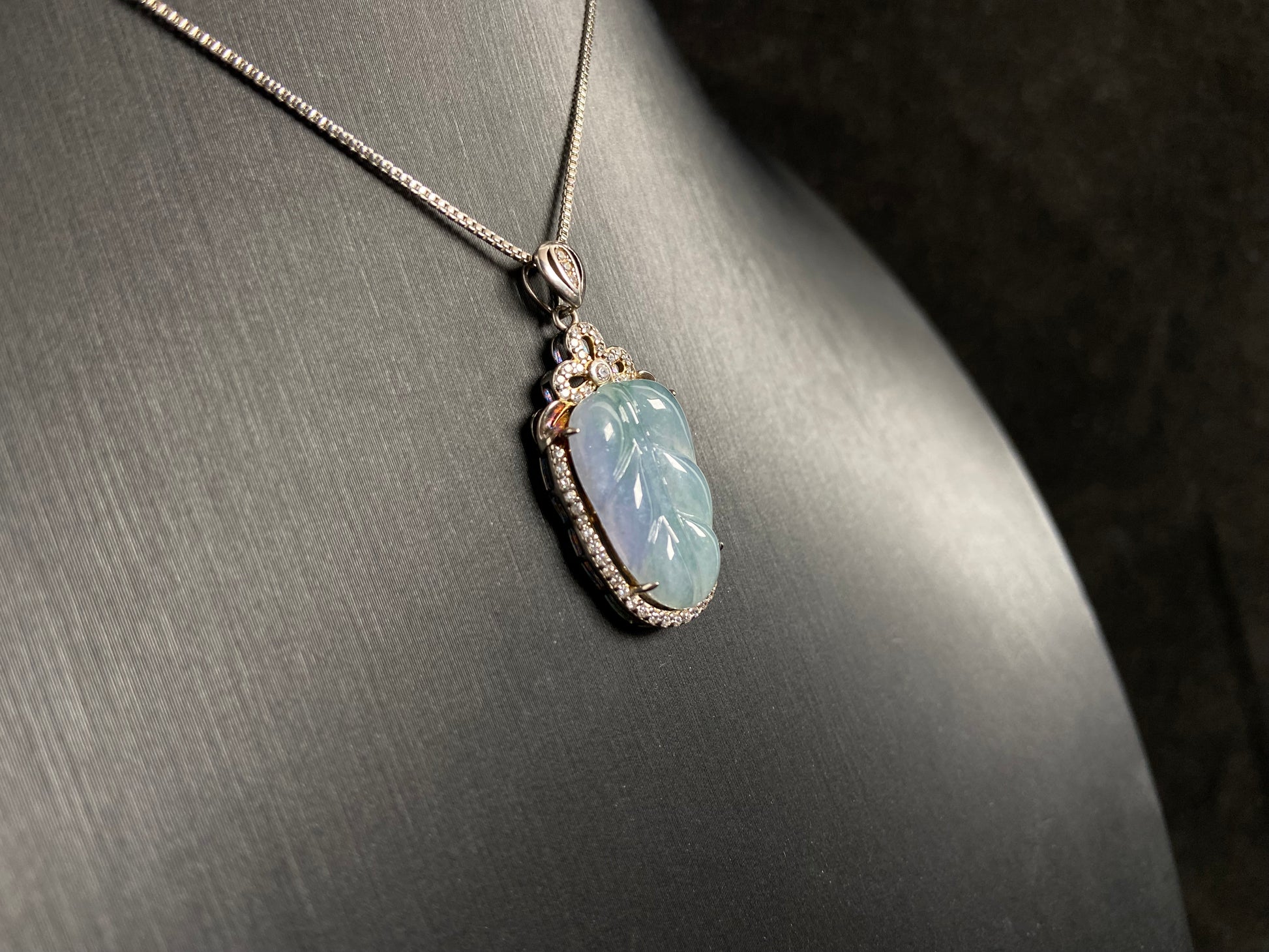 A leaf shaped jade pendant featuring translucent green blending into soft purple, elegantly framed in 925 silver.