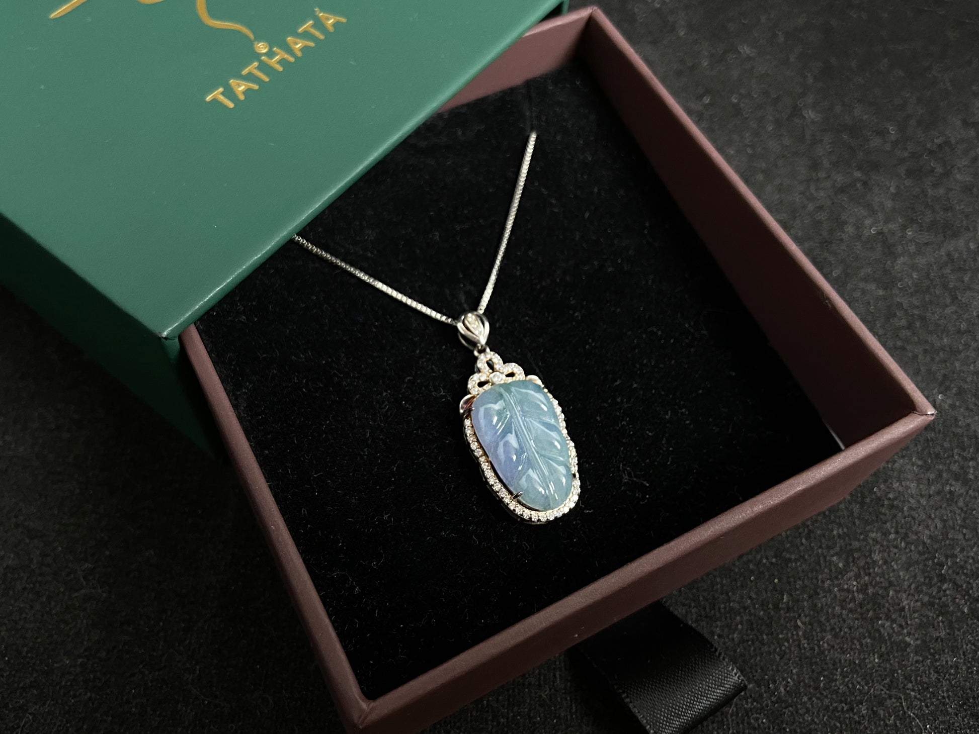 A leaf shaped jade pendant featuring translucent green blending into soft purple, elegantly framed in 925 silver.