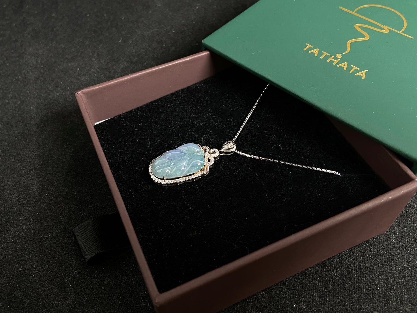 A leaf shaped jade pendant featuring translucent green blending into soft purple, elegantly framed in 925 silver.
