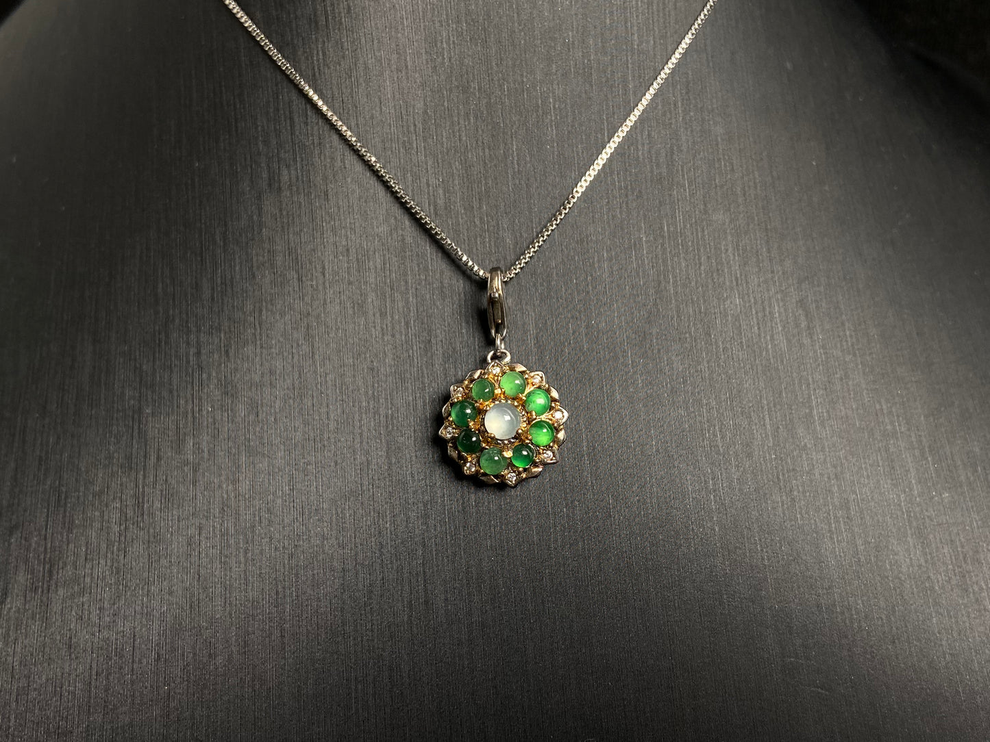 A pendant featuring a big icy center stone surrounded by eight translucent green jade beads, all set in 925 silver.
