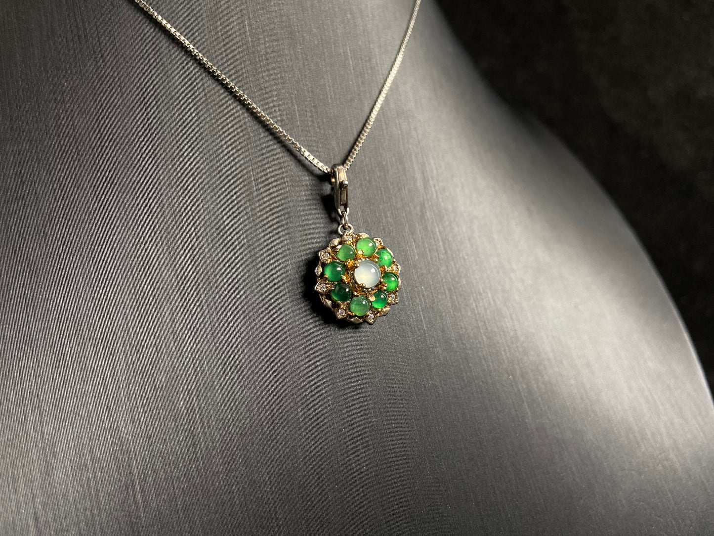 A pendant featuring a big icy center stone surrounded by eight translucent green jade beads, all set in 925 silver.