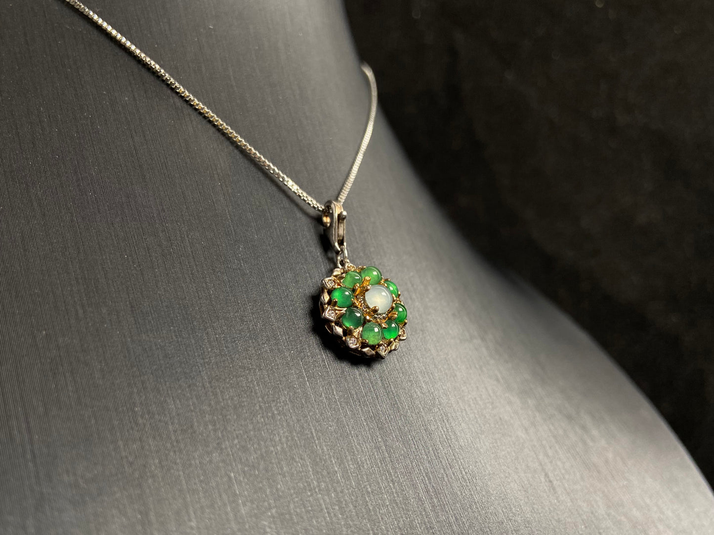 A pendant featuring a big icy center stone surrounded by eight translucent green jade beads, all set in 925 silver.