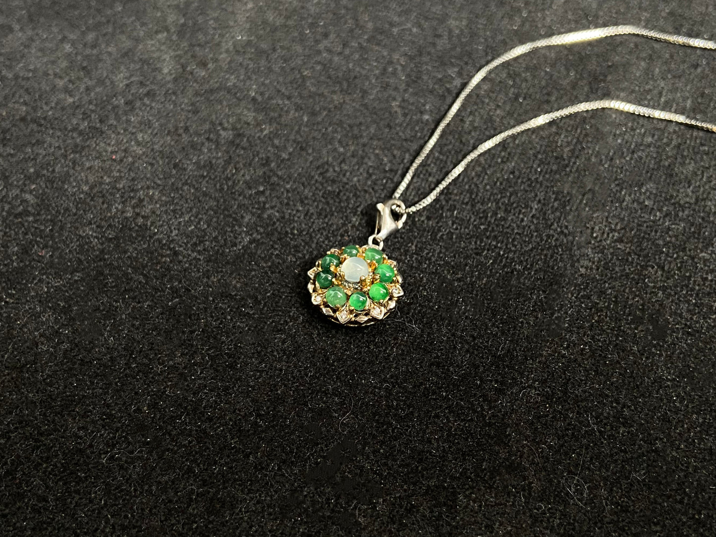 A pendant featuring a big icy center stone surrounded by eight translucent green jade beads, all set in 925 silver.