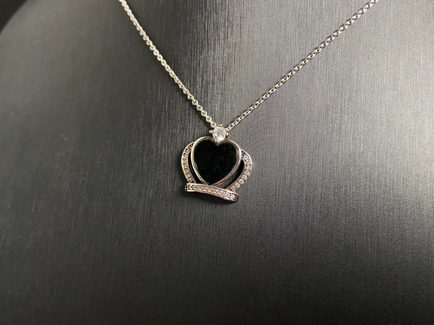 A heart shaped mystical jade pendant set in 925 silver with a diamond accent, revealing a hidden green glow when illuminated.