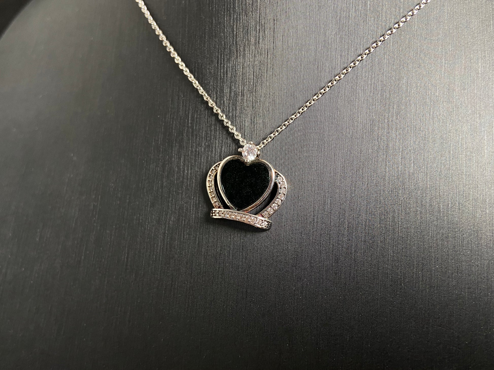 A heart shaped mystical jade pendant set in 925 silver with a diamond accent, revealing a hidden green glow when illuminated.