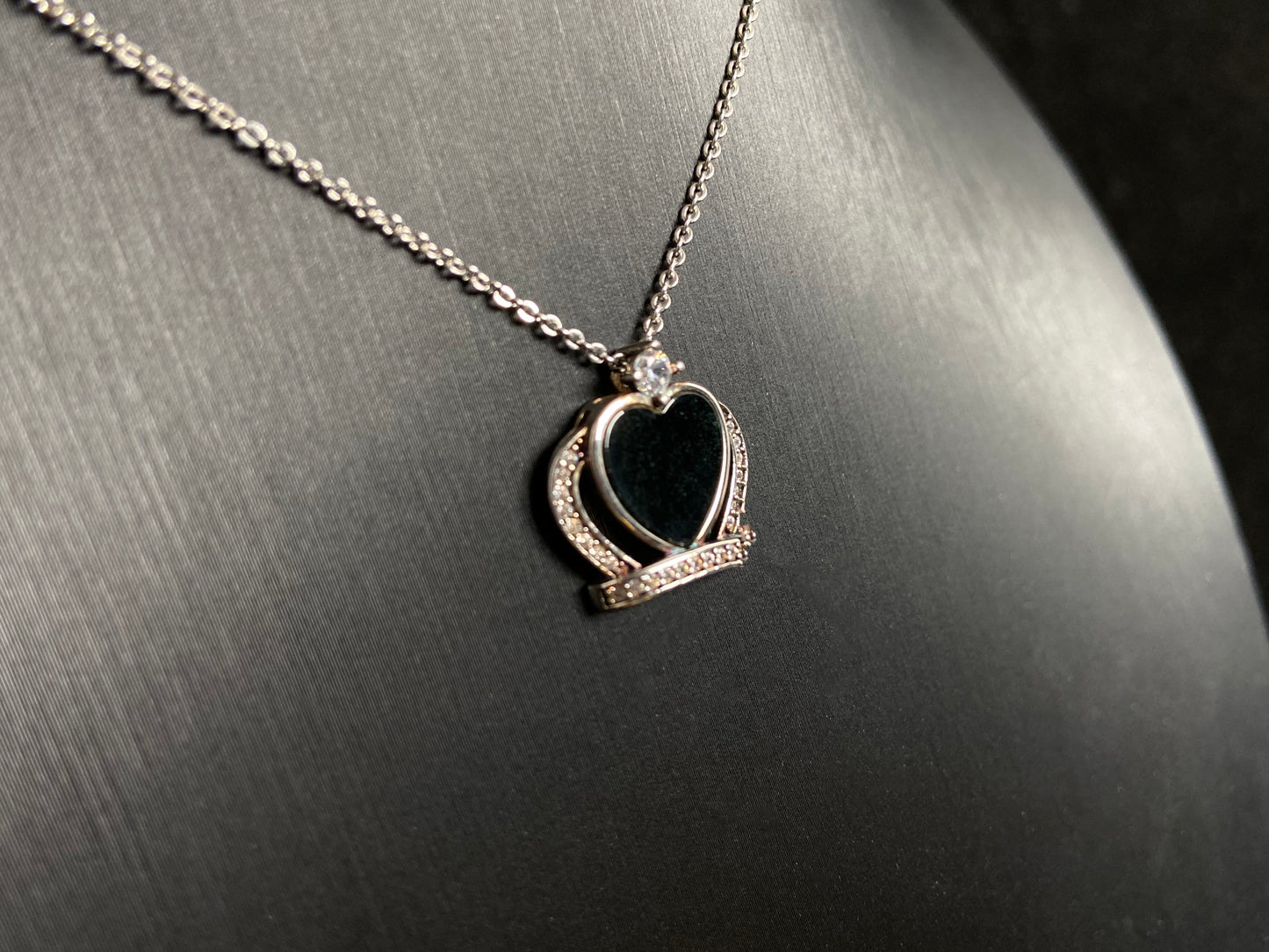 A heart shaped mystical jade pendant set in 925 silver with a diamond accent, revealing a hidden green glow when illuminated.