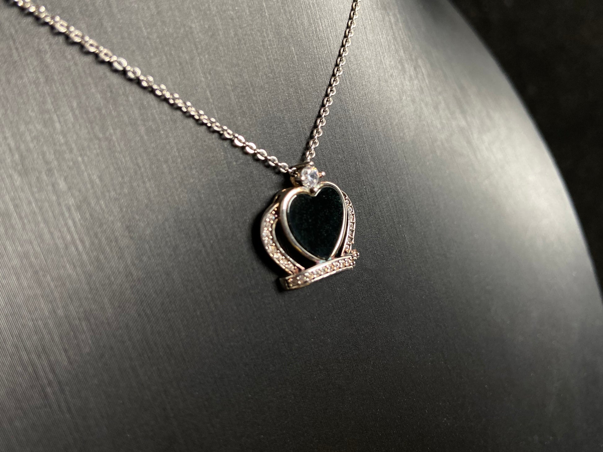 A heart shaped mystical jade pendant set in 925 silver with a diamond accent, revealing a hidden green glow when illuminated.