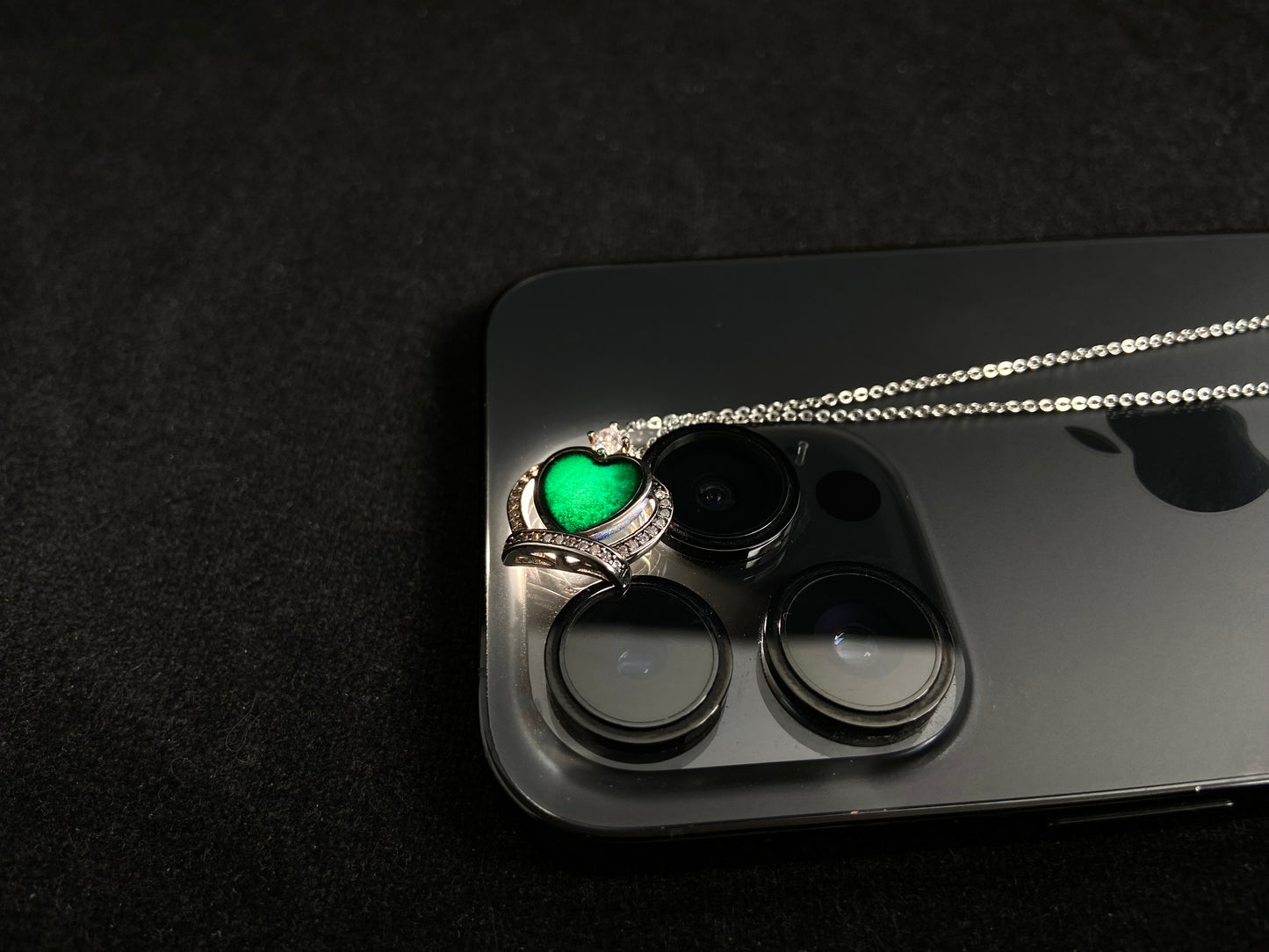 A heart shaped mystical jade pendant set in 925 silver with a diamond accent, revealing a hidden green glow when illuminated.