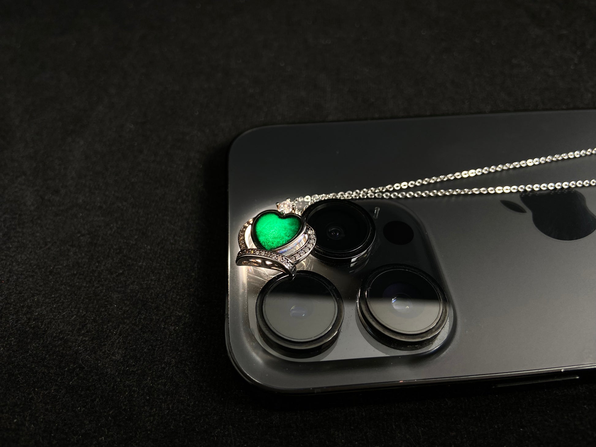 A heart shaped mystical jade pendant set in 925 silver with a diamond accent, revealing a hidden green glow when illuminated.