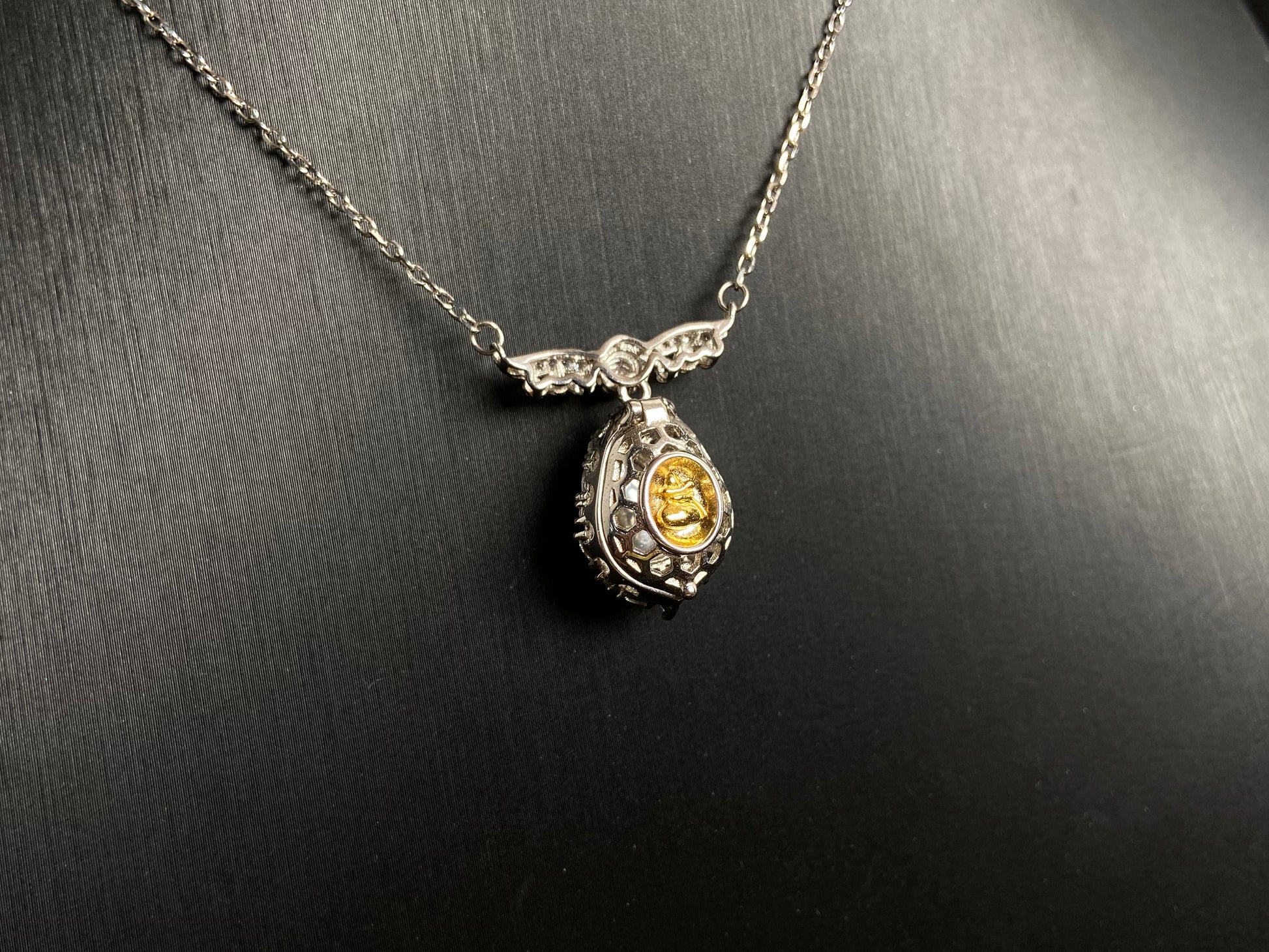 A silver framed green jadeite Gourd pendant, topped with a bead and backed by a gold money bag symbolizing wealth and power.