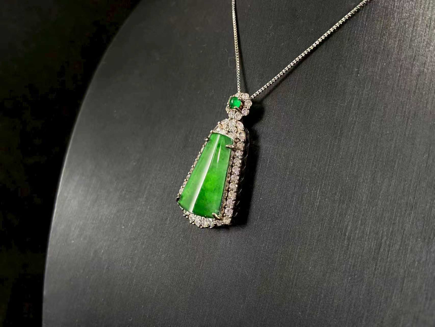 A transparent green jade “harmony plaque” symbolizing peace and freedom from worldly troubles, is elegantly framed in 925 sterling silver.