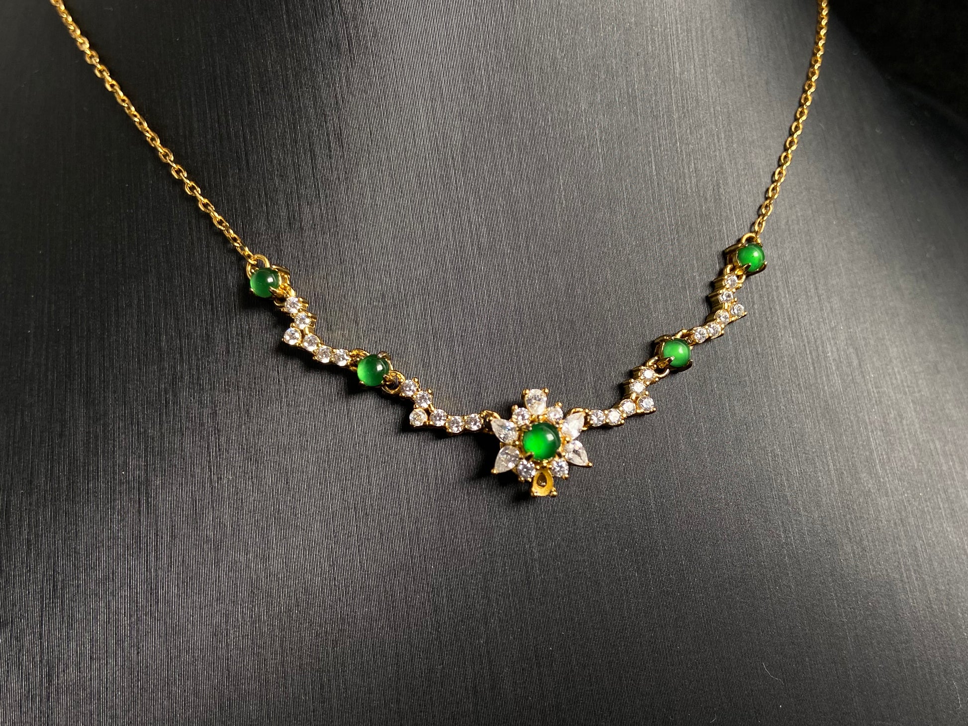 A pendant with five green jade beads one centered in a gold plated 925 silver floral setting, flanked by four accent beads.