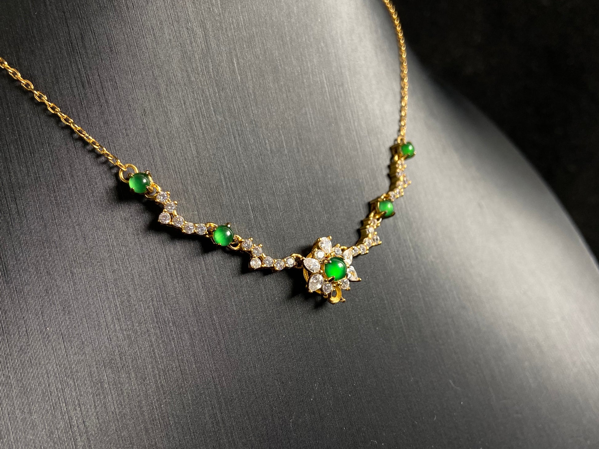 A pendant with five green jade beads one centered in a gold plated 925 silver floral setting, flanked by four accent beads.