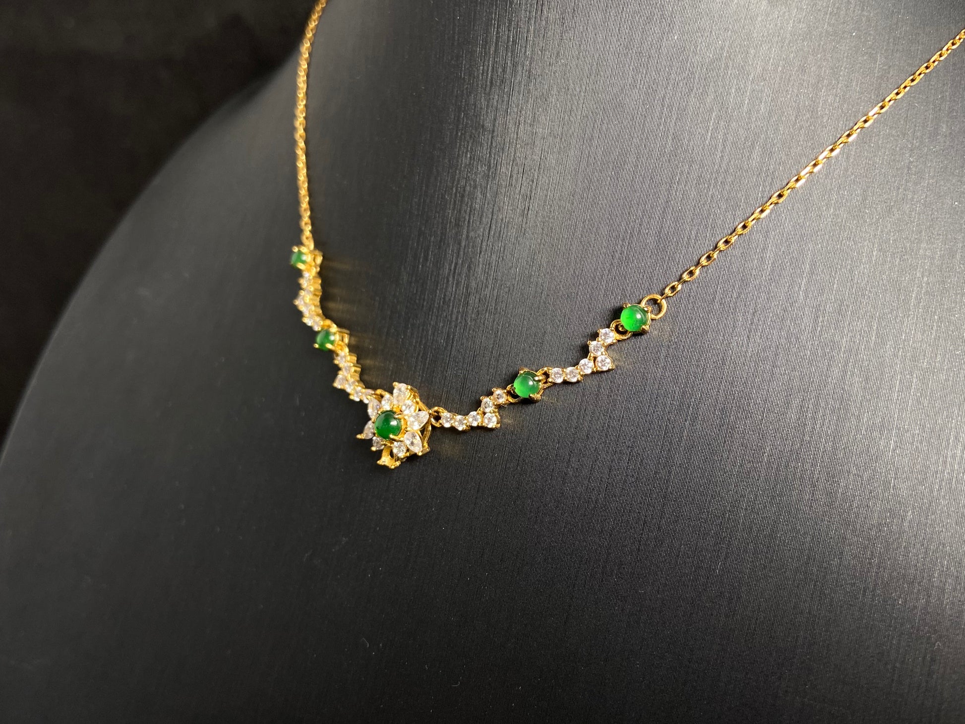 A pendant with five green jade beads one centered in a gold plated 925 silver floral setting, flanked by four accent beads.
