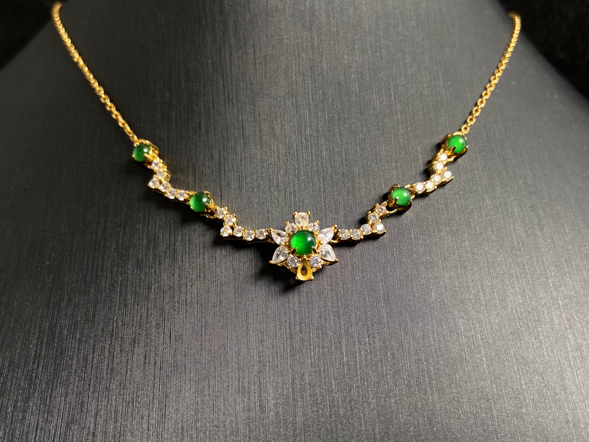 A pendant with five green jade beads one centered in a gold plated 925 silver floral setting, flanked by four accent beads.