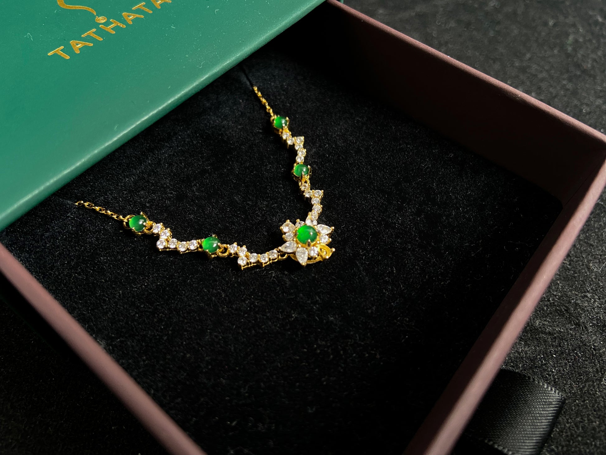 A pendant with five green jade beads one centered in a gold plated 925 silver floral setting, flanked by four accent beads.