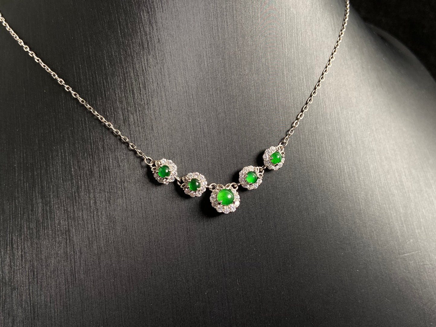A jadeite pendant featuring five green beads exquisitely set in 925 silver.
