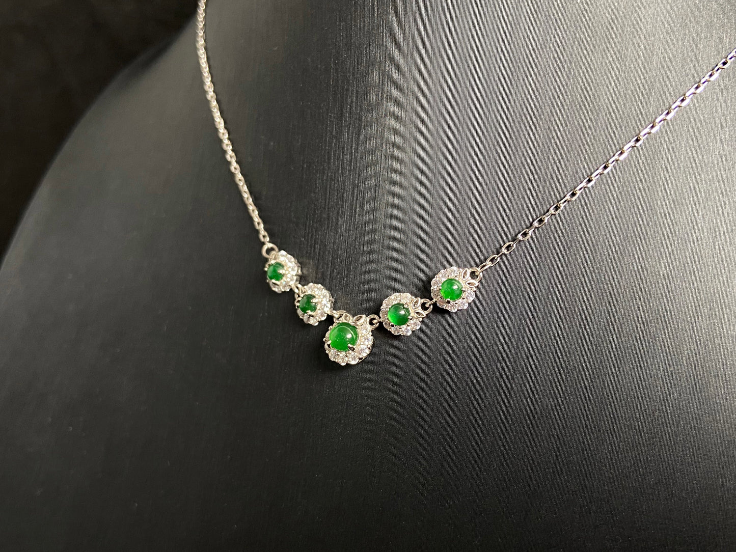 A jadeite pendant featuring five green beads exquisitely set in 925 silver.