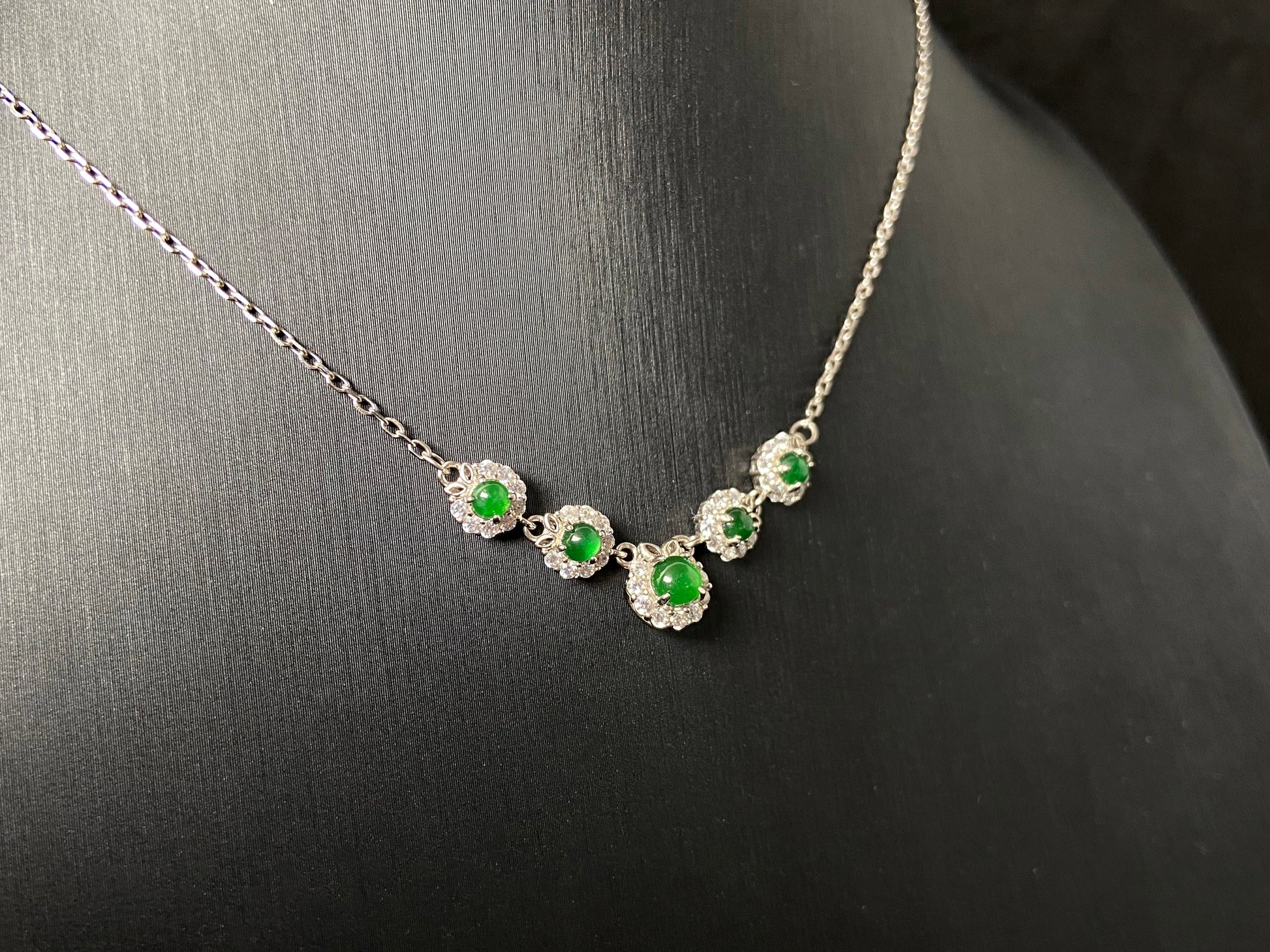A jadeite pendant featuring five green beads exquisitely set in 925 silver.
