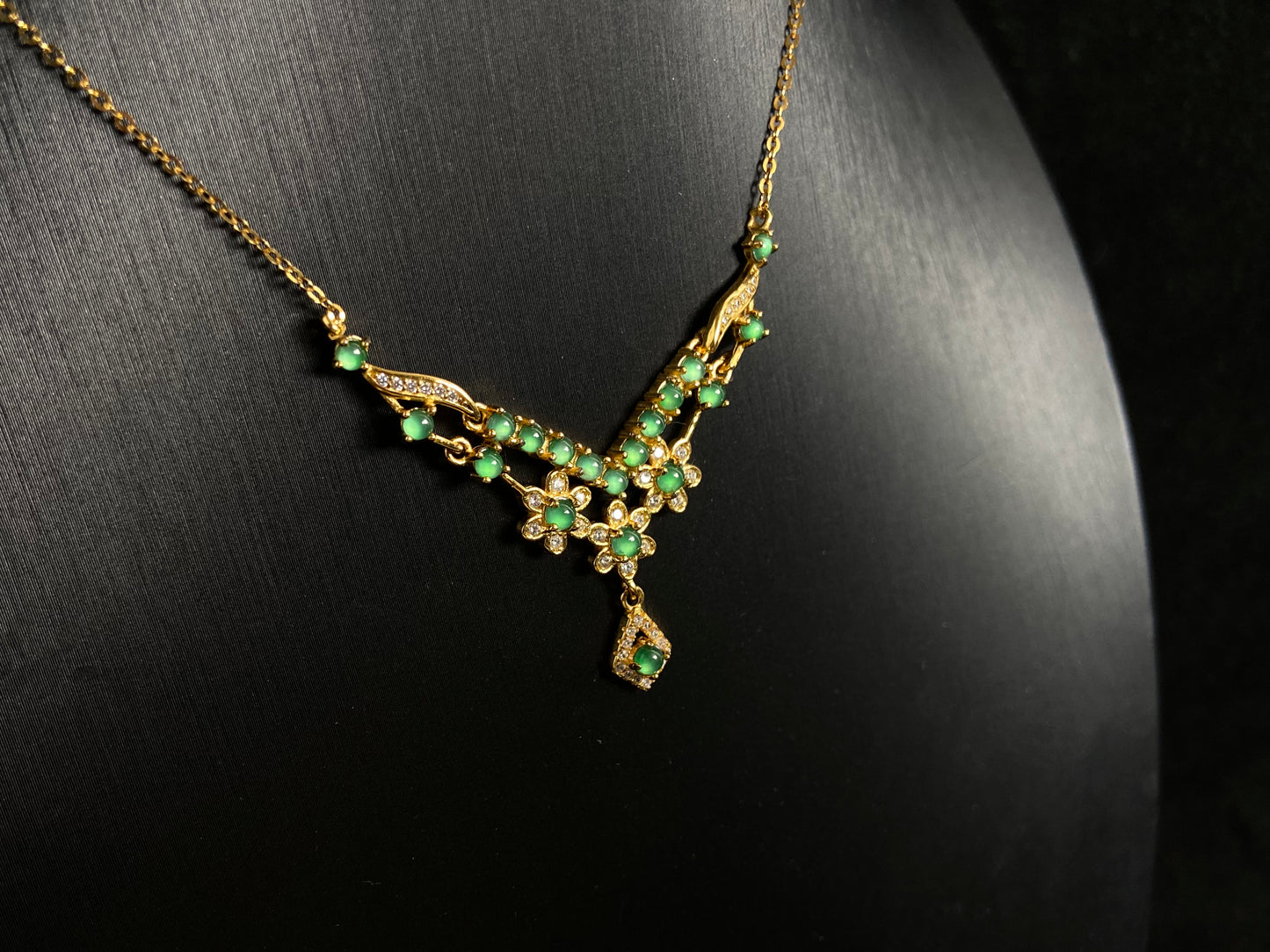 A delicate pendant featuring 19 transparent green jade beads, elegantly set in gold plated 925 silver.