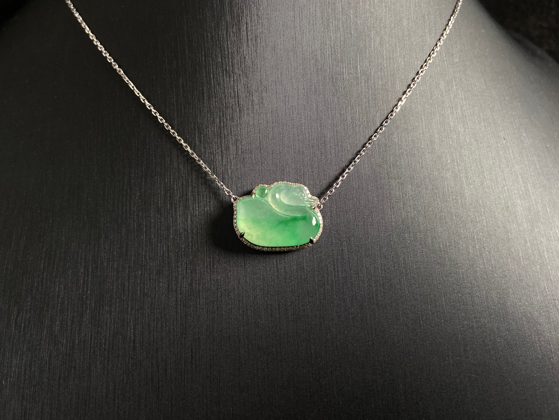 This jadeite pendant features a light green, translucent swan with deep green inclusions, elegantly set in 18K gold.