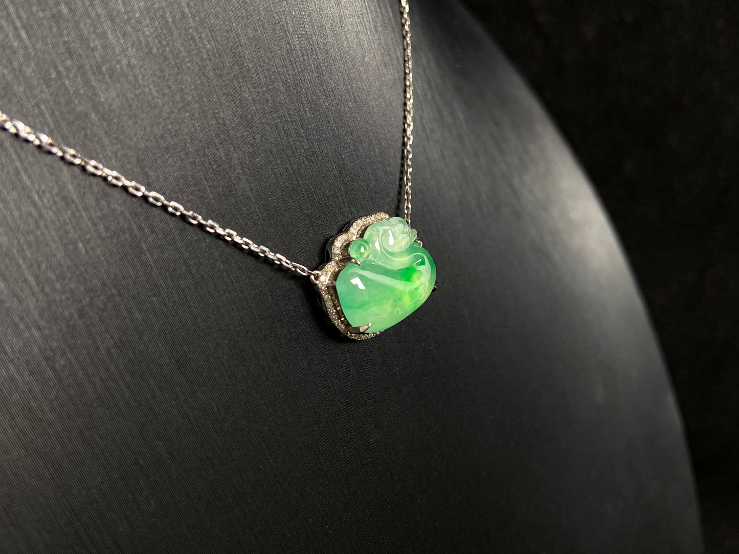 This jadeite pendant features a light green, translucent swan with deep green inclusions, elegantly set in 18K gold.