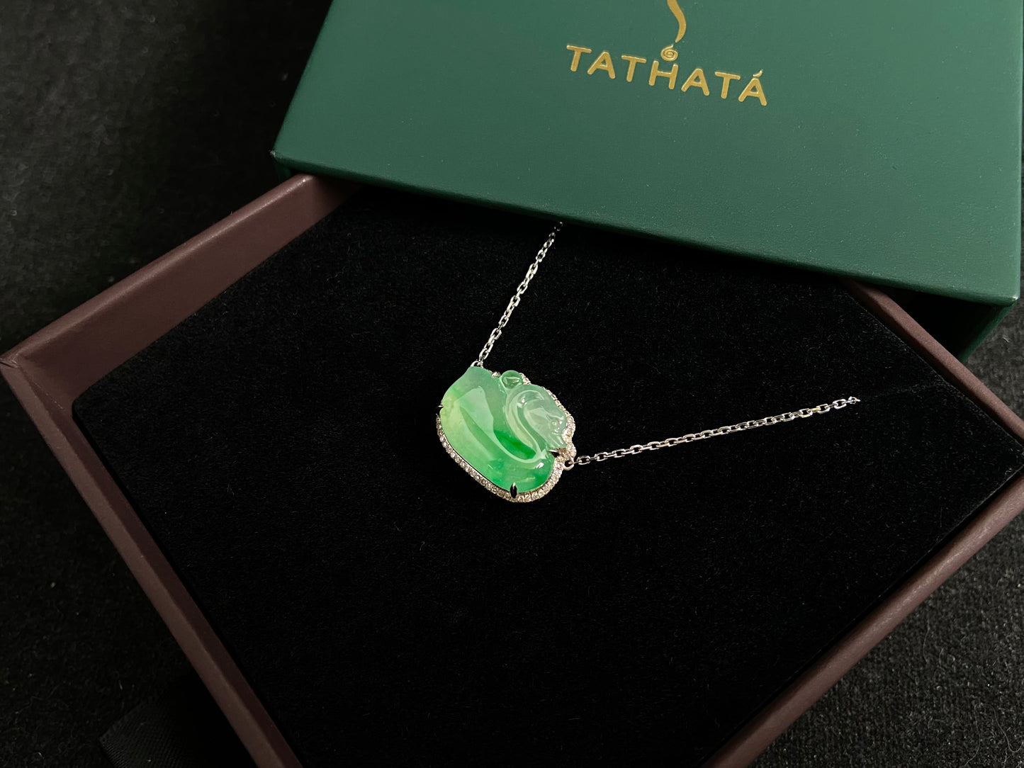 This jadeite pendant features a light green, translucent swan with deep green inclusions, elegantly set in 18K gold.