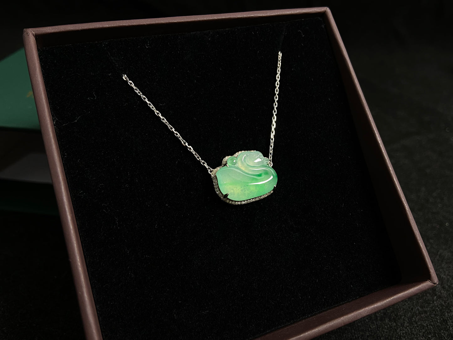 This jadeite pendant features a light green, translucent swan with deep green inclusions, elegantly set in 18K gold.