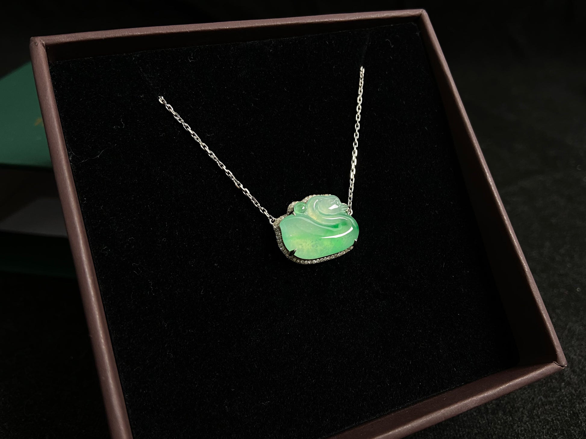 This jadeite pendant features a light green, translucent swan with deep green inclusions, elegantly set in 18K gold.