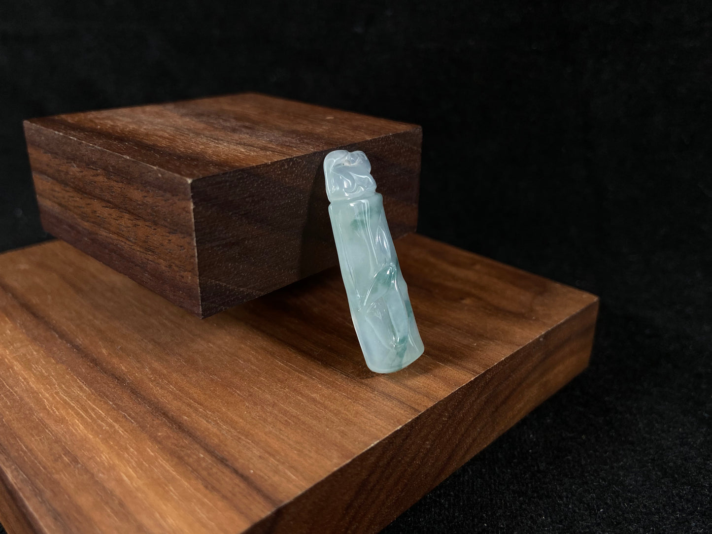 A translucent bamboo shaped jade pendant with floating green accents, symbolizing continual growth and career success.