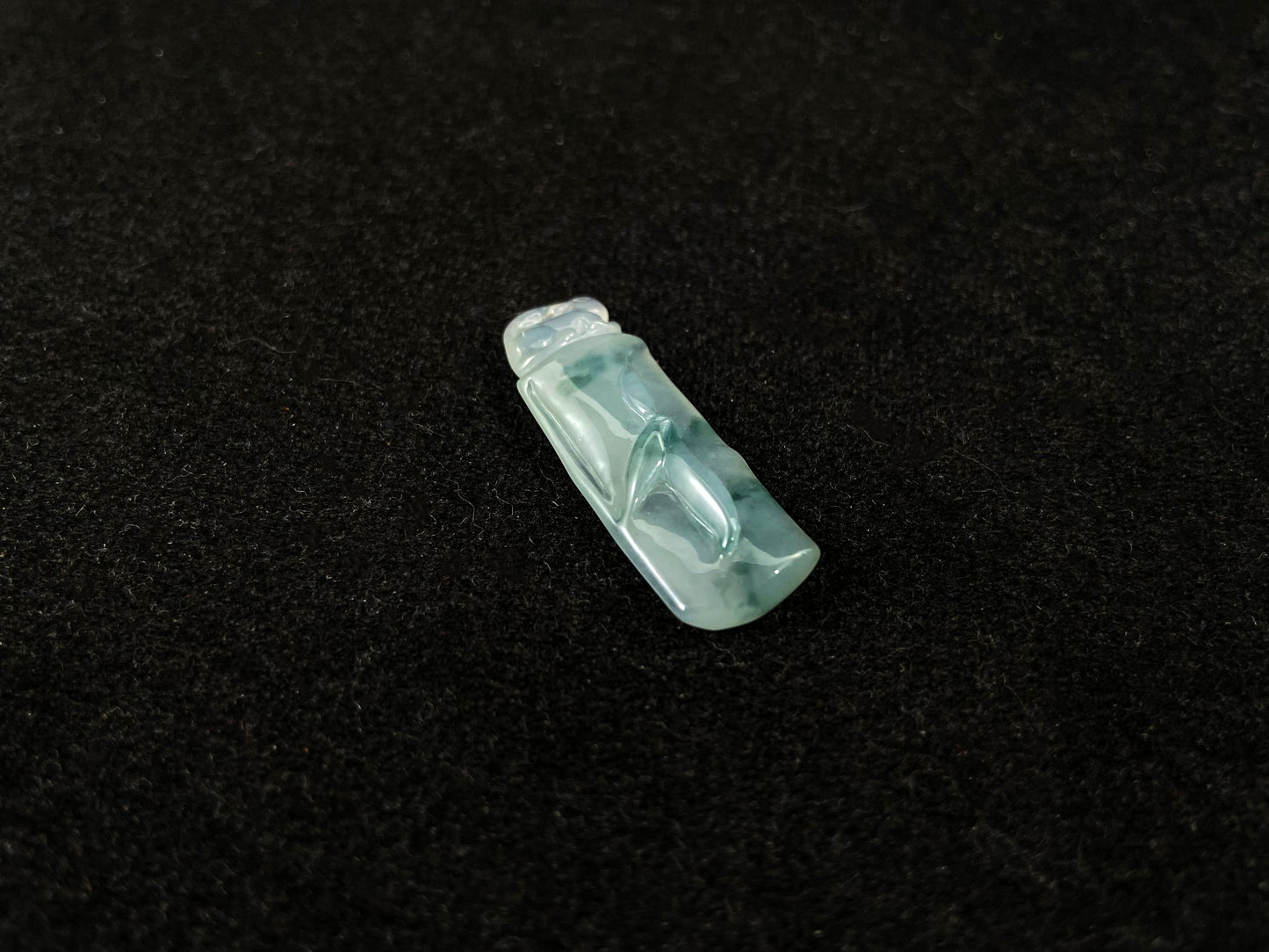 A translucent bambooc shaped jade pendant with floating green accents, symbolizing continual growth and career success.